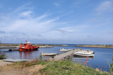 A boat anchored in an old small harbour, grass in the foreground