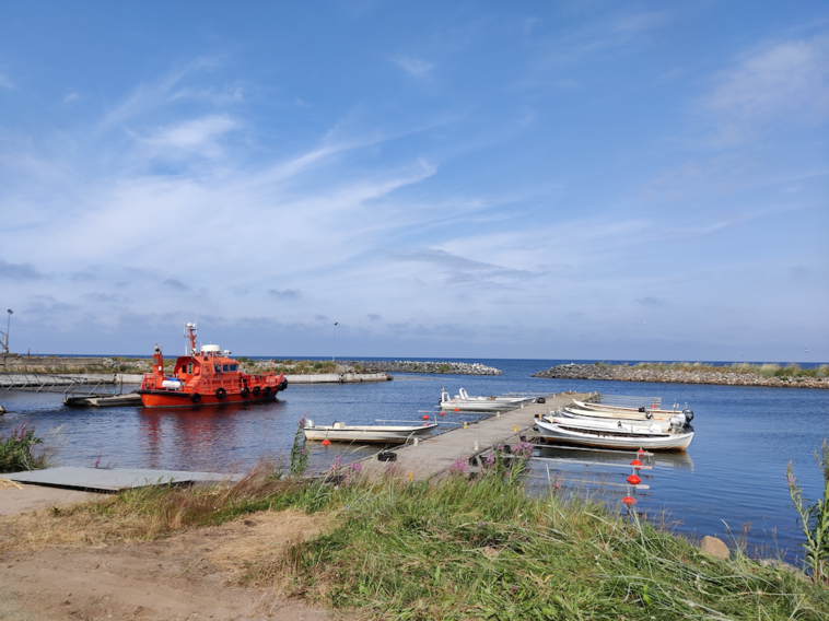 A boat anchored in an old small harbour, grass in the foreground