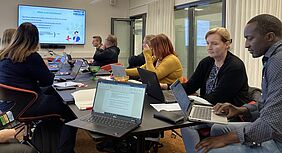 People sitting around a table working on laptops